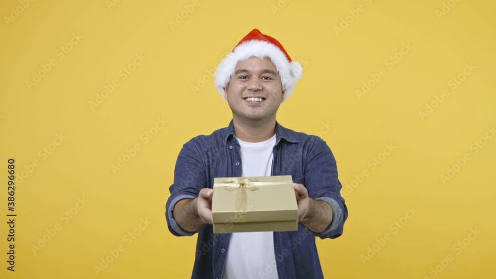 Happy excited asian man in new year's christmas day holding the present gift box on isolated yellow background. Man getting the gift from santa claus. 4K Resolution. Happy excited asian man in new year's christmas day holding the present gift box on isolated yellow background. Man getting the gift from santa claus. 4K Resolution.