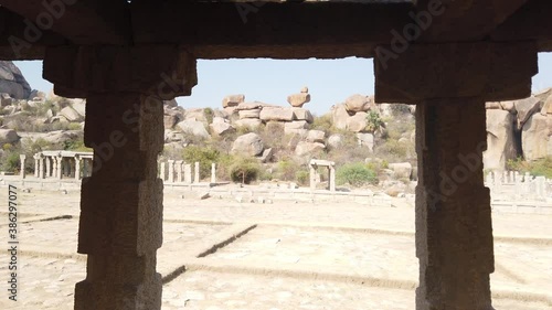 Tracking Shot Past Colonnade Pillar of Ruined Temple at Hampi Archaeological Site, Karnataka, India photo