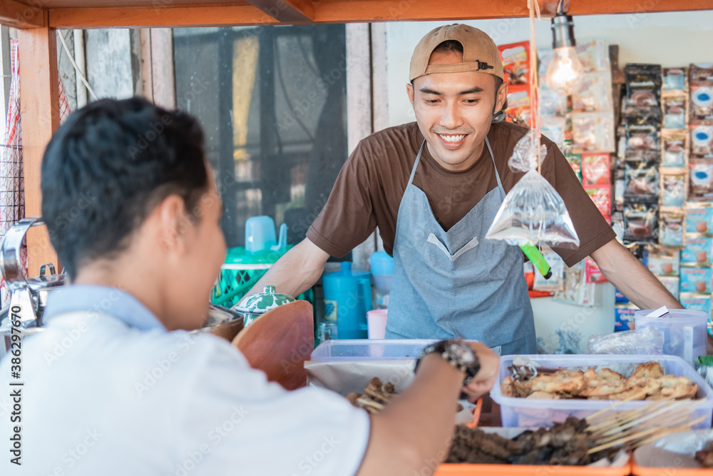 angkringan man seller smiles while serving customers at the cart stall angkringan man seller smiles while serving customers at the cart stall