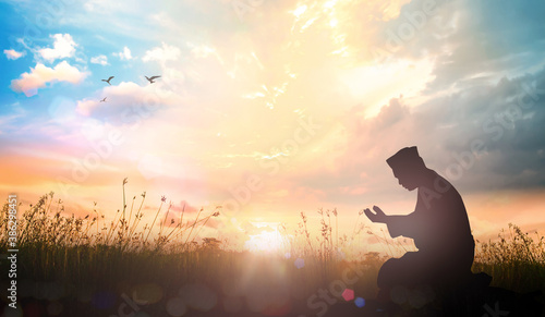 Muslim dua to Allah over meadow sunset background photo