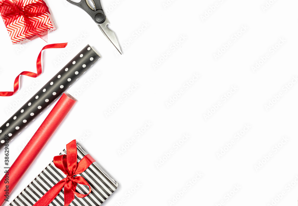 Gift boxes wrapped in black and white striped and red paper with wrapping materials over white background. Various designs wrapped presents preparation. Copy space.