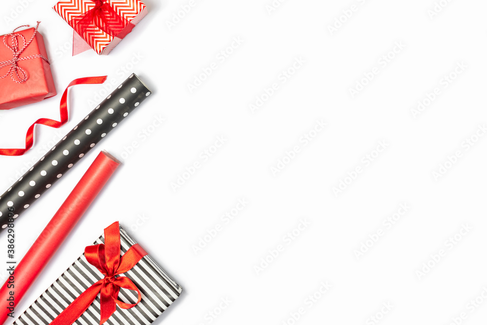 Gift boxes wrapped in black and white striped and red paper with wrapping materials over white background. Various designs wrapped presents preparation. Copy space.