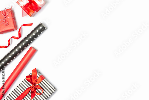 Obraz na płótnie Gift boxes wrapped in black and white striped and red paper with wrapping materials over white background. Various designs wrapped presents preparation. Copy space. w salonie