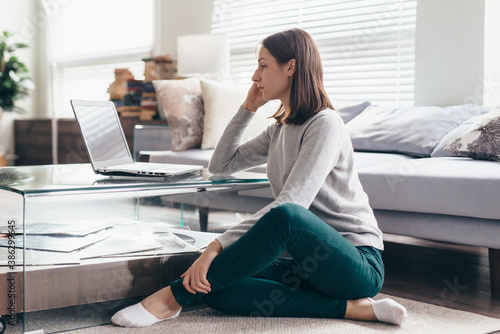 Side view of a woman working on notebook computer sitting at home.