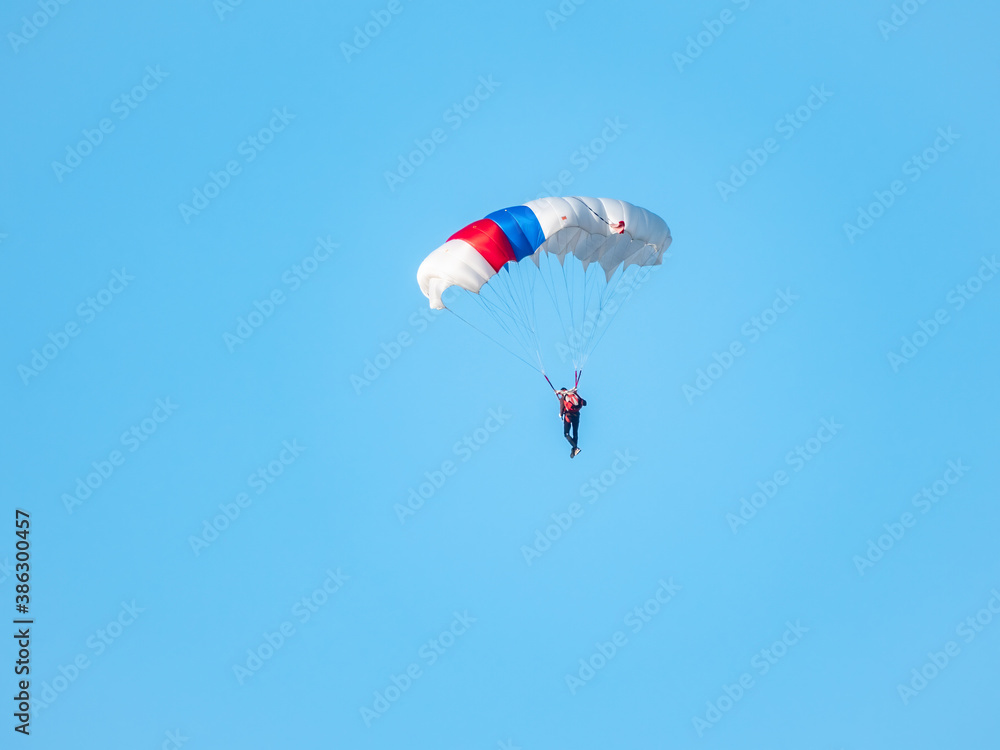 one parachutist floats slowly at low altitude on the background of clear sky one parachutist floats slowly at low altitude on the background of clear sky