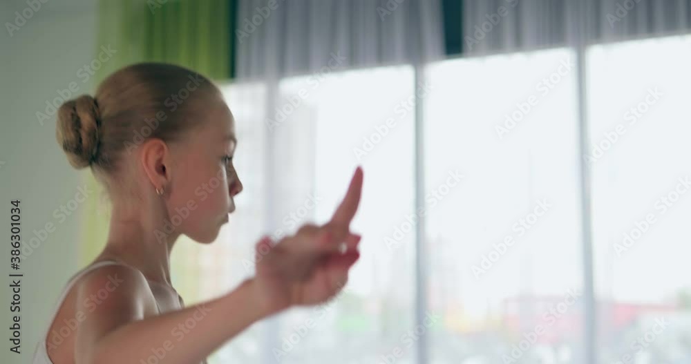 Concentrated girl in white suit dances doing classical ballet spins at window in studio closeup slow motion Concentrated girl in white suit dances doing classical ballet spins at window in studio closeup slow motion