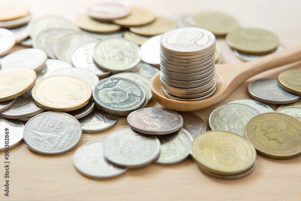 Coins stack on wooden spoon with sunlight for money saving concept Coins stack on wooden spoon with sunlight for money saving concept