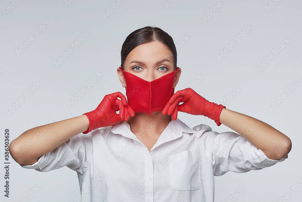 attractive girl in red gloves and a face mask. The concept of prevention of coronavirus covid 19. Photo session in the studio on a white background attractive girl in red gloves and a face mask. The concept of prevention of coronavirus covid 19. Photo session in the studio on a white background