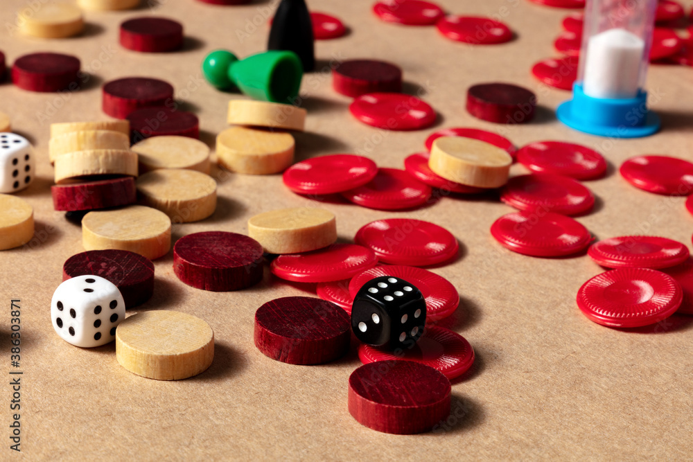 Board games concept, various pieces and dice, scattered on a table on a brown background Board games concept, various pieces and dice, scattered on a table on a brown background