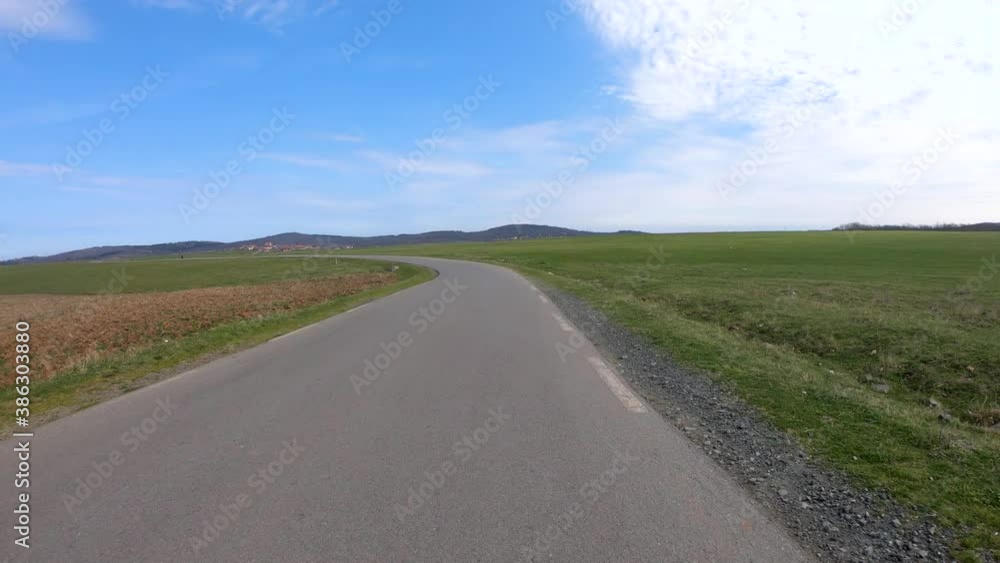 Cycling on an empty asphalt road between a green meadow and plowed field. Blue sky with white clouds. Countryside landscape in Bulgaria. Pov. Cycling on an empty asphalt road between a green meadow and plowed field. Blue sky with white clouds. Countryside landscape in Bulgaria. Pov.