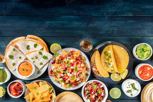 Mexican food background with copy space. Many various dishes, overhead shot on a dark blue wooden background