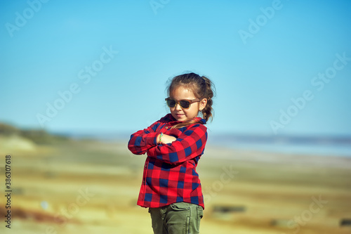 Portrait of a little girl in nature . The child wears a comfortable shirt and jeans .The concept of casual wear