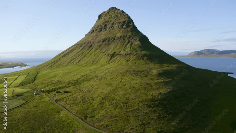 Mesmerizing aerial view of isolated green volcanic mountain with sea in background, on a bright sunny day. Iceland. Mesmerizing aerial view of isolated green volcanic mountain with sea in background, on a bright sunny day. Iceland.