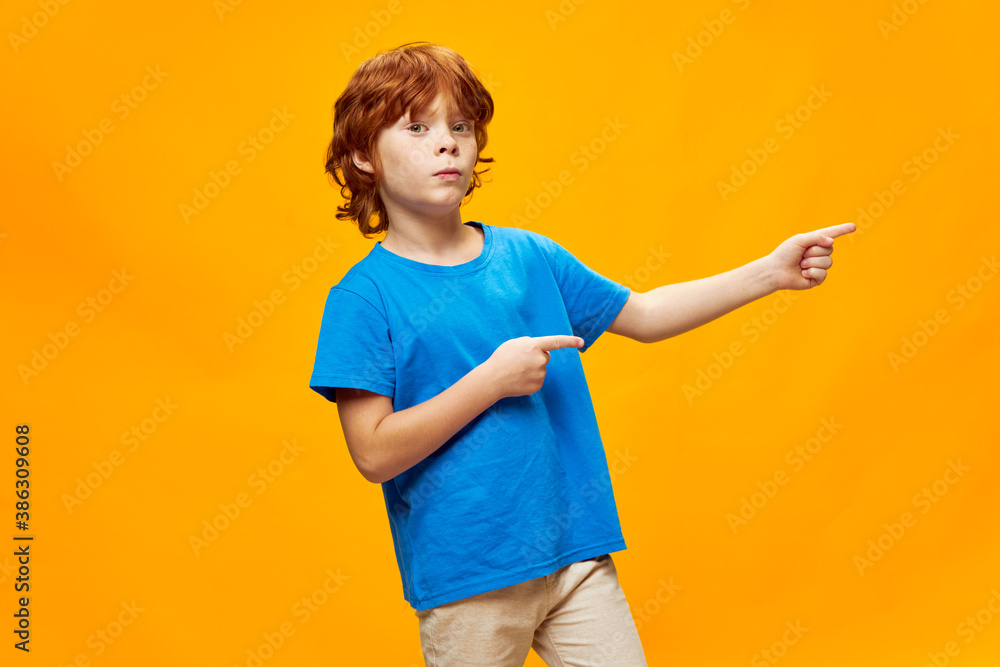 boy with red hair shows two hands with the index finger to the side blue t-shirt Copy Space boy with red hair shows two hands with the index finger to the side blue t-shirt Copy Space