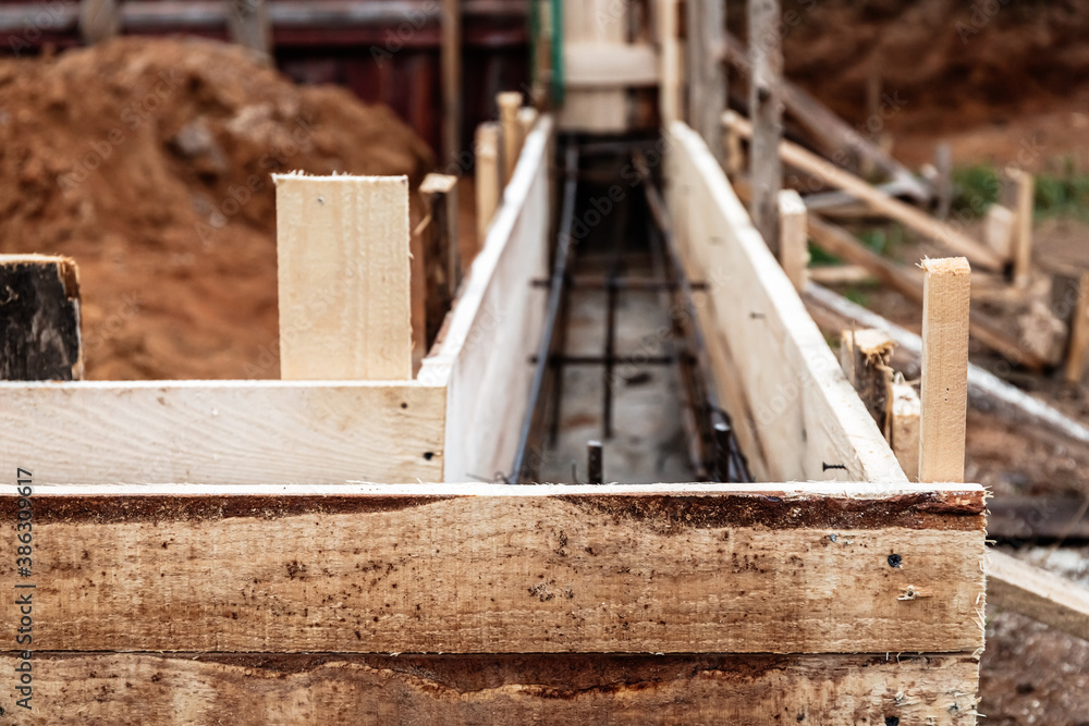 Timber formwork with metal reinforcement for pouring concrete and creating a solid foundation for a building or fence. Construction process