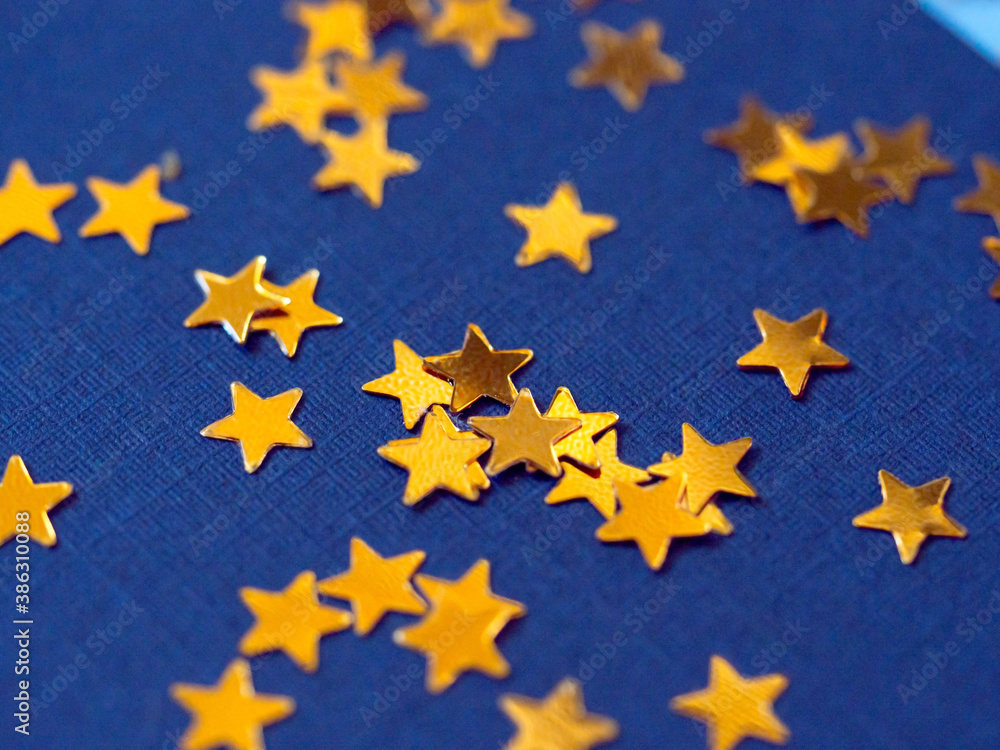 Gold star glitter confetti splashed on blue paper background. Gold star glitter confetti splashed on blue paper background.