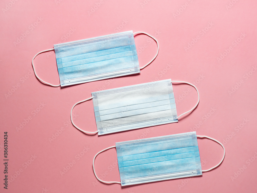 Medical protective mask on a pastel pink background. Individual, disposable surgical face mask flat lay pattern. Quarantine healthcare, hygiene and coronavirus protection concept Medical protective mask on a pastel pink background. Individual, disposable surgical face mask flat lay pattern. Quarantine healthcare, hygiene and coronavirus protection concept