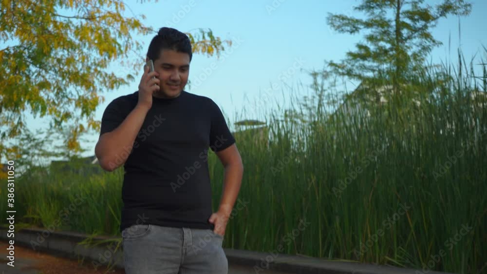 Young man is having a phone conversation while walking in a suburban neighborhood Young man is having a phone conversation while walking in a suburban neighborhood