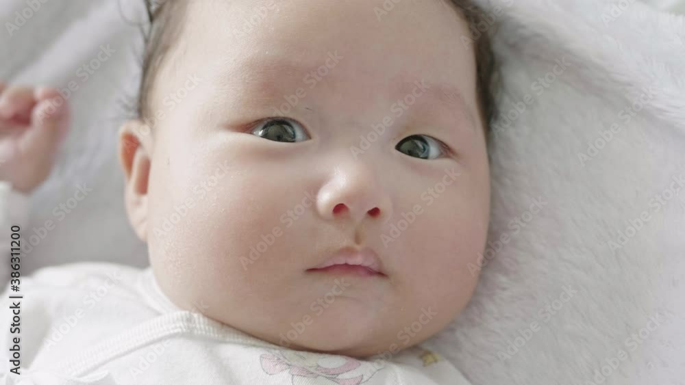 Close up shot of a mixed Asian baby's face as she lays on the bed, looking around. Close up shot of a mixed Asian baby's face as she lays on the bed, looking around.