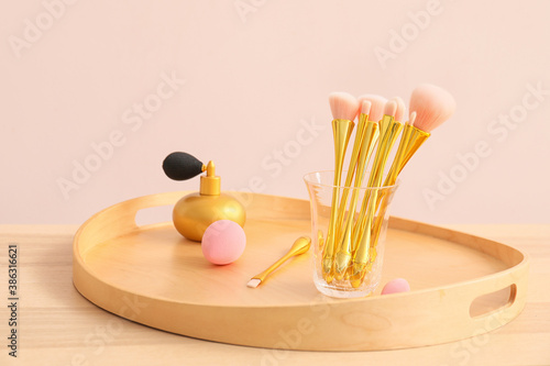 Set of makeup brushes with perfume bottle on table