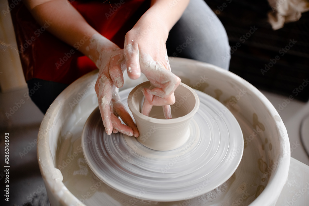Female hands crafting a pottery cup on a potter's wheel. Handmade and crafting concept. Top horizontal view copyspace.