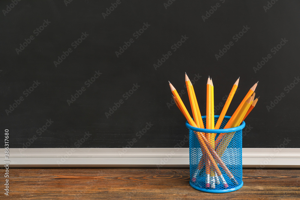 Holder with pencils on table in classroom - obrazy, fototapety, plakaty 