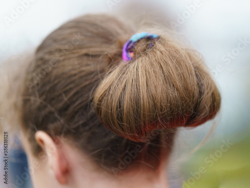 Modern Teen Hairstyle. Youth fashion. The girl putting her hair back in a ponytail. She using / wearing scrunch