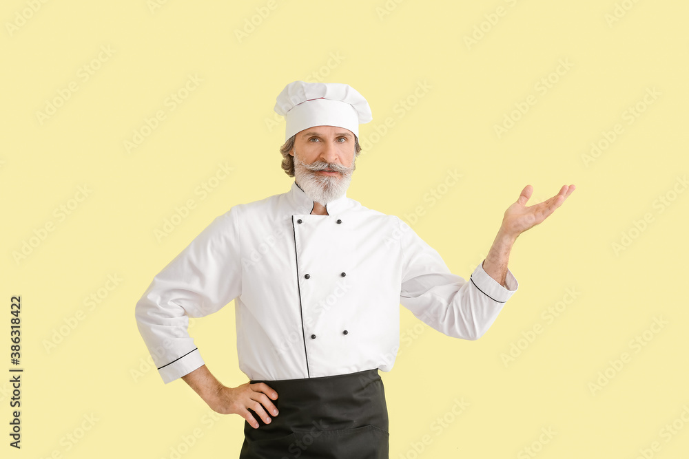 Mature male chef showing something on color background Mature male chef showing something on color background