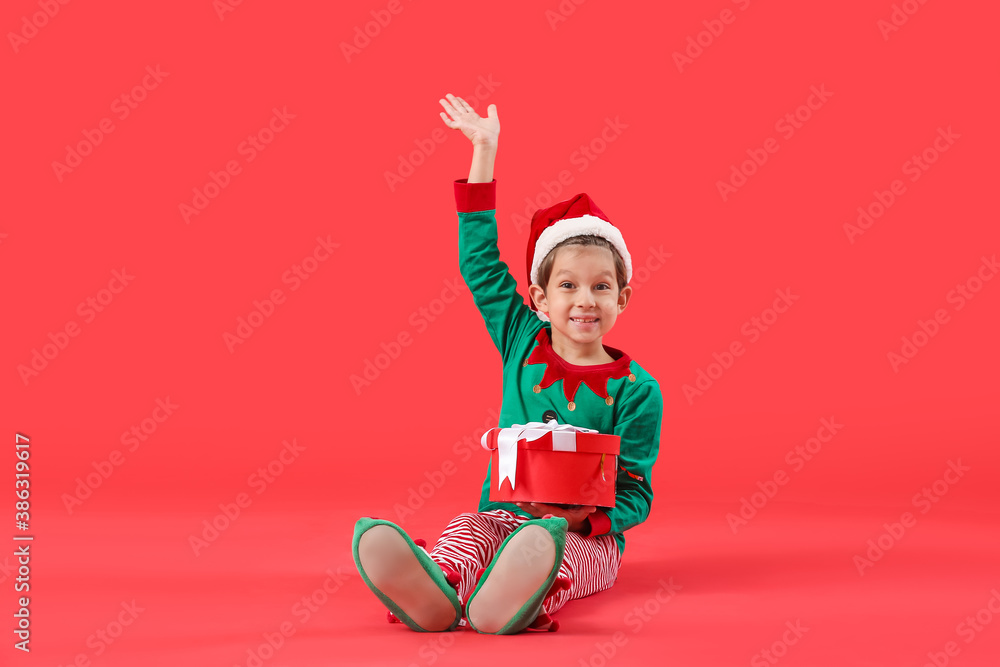 Obraz premium Cute little elf with Christmas gift on color background