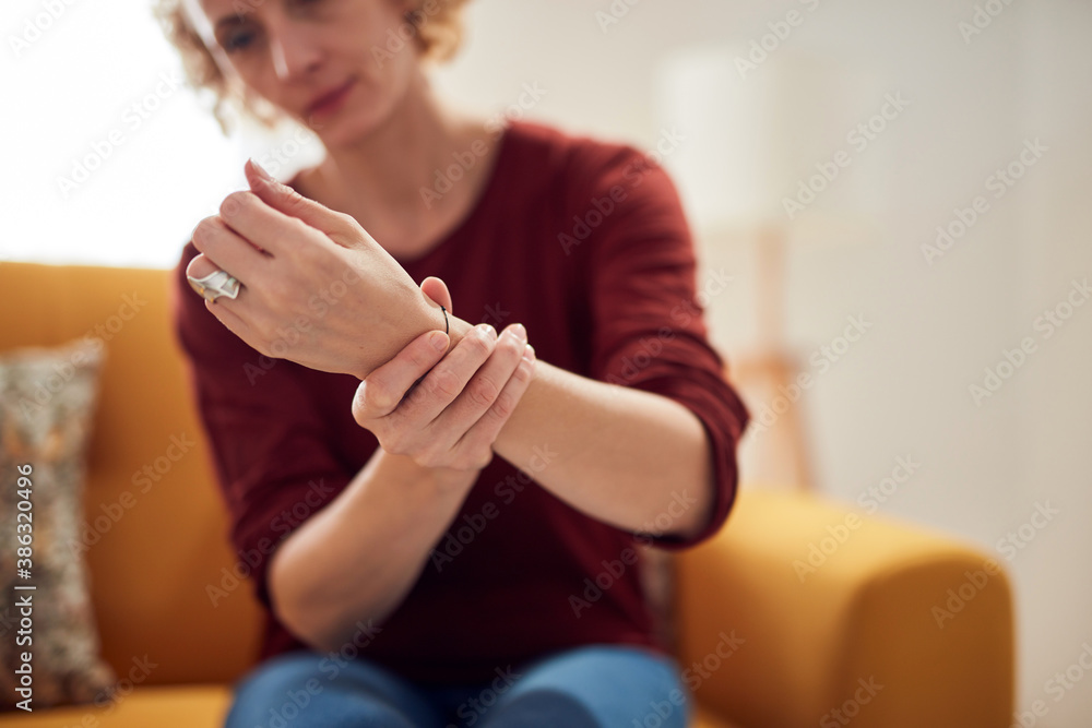 Obraz premium Woman with hand pain sitting on a couch at home.