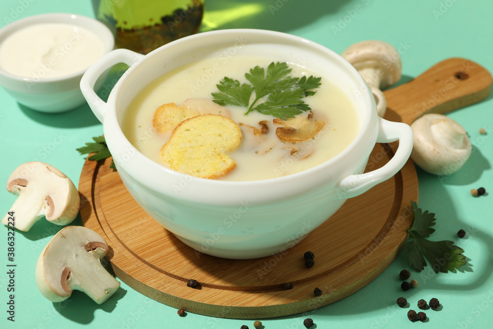Concept of tasty lunch with bowl of mushroom soup on mint background Concept of tasty lunch with bowl of mushroom soup on mint background