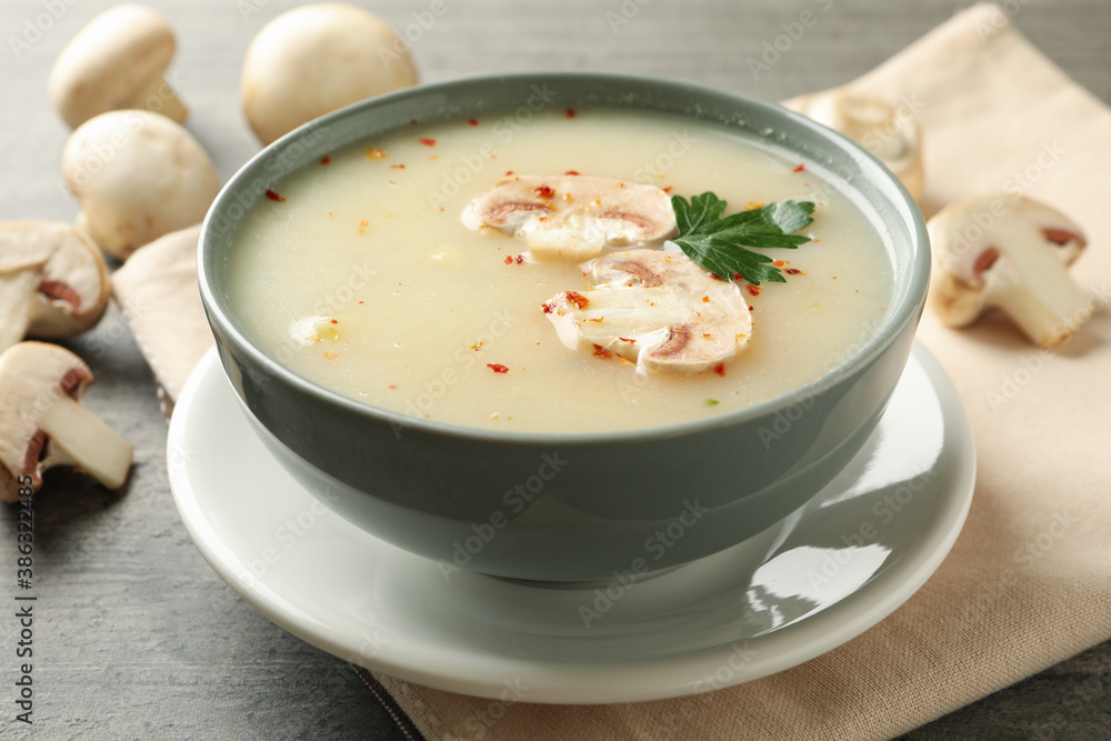 Concept of tasty lunch with bowl of mushroom soup on gray background