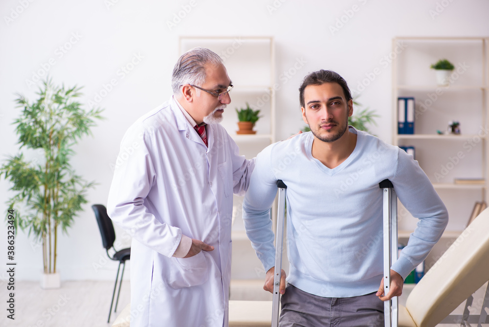 Young leg injured man visiting old doctor osteopath Young leg injured man visiting old doctor osteopath