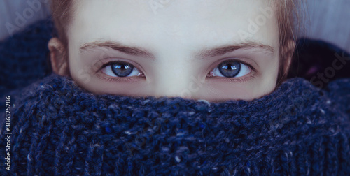 Beautiful girl with blue eyes wrapped herself in a warm blue knitted sweater