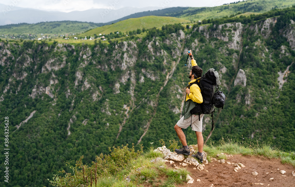 Hiker with backpacks reaches the summit of mountain peak. Success, freedom and happiness concept Hiker with backpacks reaches the summit of mountain peak. Success, freedom and happiness concept