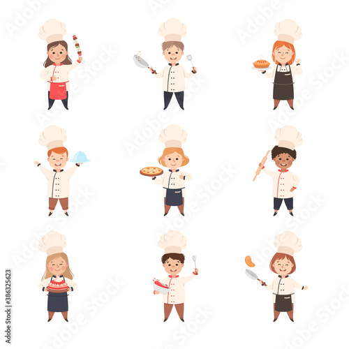 Children Chefs Cooking in Kitchen, Kids in Uniform and Hats Holding Platters with Freshly Prepared Dishes Cartoon Style Vector Illustration