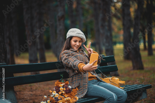 Teenage girl taking selfie in the park on autumn day