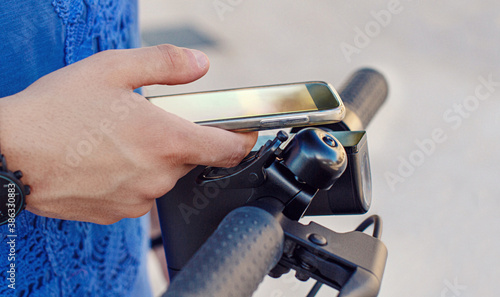 Young man using smartphone to unlock a shared electric scooter