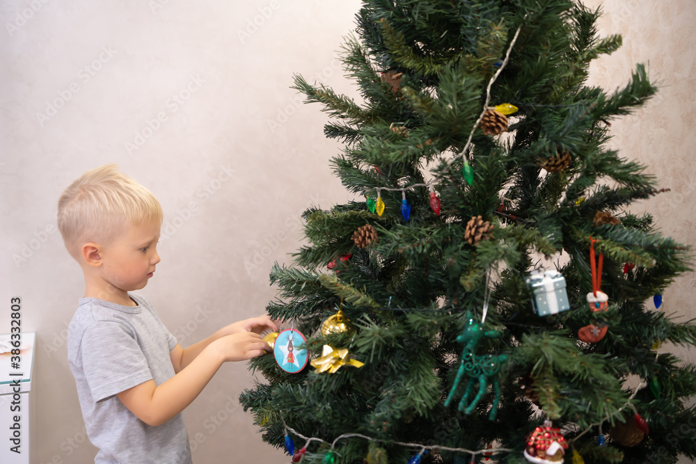 A 5 year old blonde boy decorates a Christmas tree in a homely atmosphere. Festive mood. Home comfort. Life style. A 5 year old blonde boy decorates a Christmas tree in a homely atmosphere. Festive mood. Home comfort. Life style.