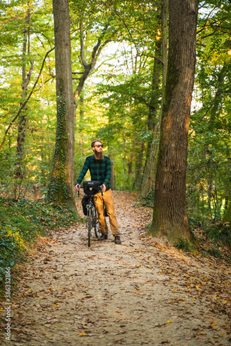 Attractive hipster man with bicycle at a public park during autumn.