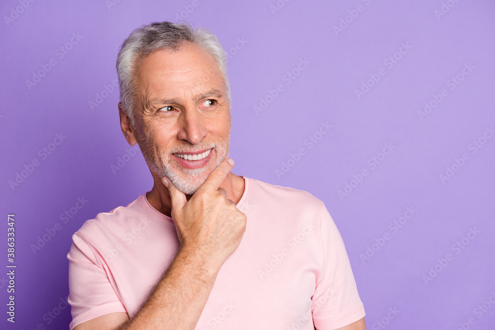 Photo of pensioner grandpa hand chin shiny smile look side empty space wear pink t-shirt isolated violet color background Photo of pensioner grandpa hand chin shiny smile look side empty space wear pink t-shirt isolated violet color background