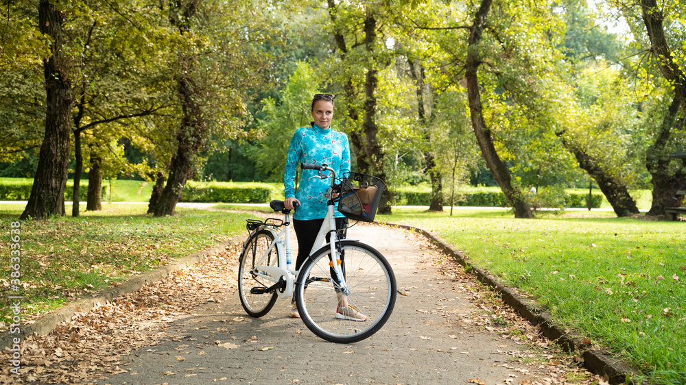 Portrait of woman with bicycle during sunrise at park, Zagreb, Croatia.
