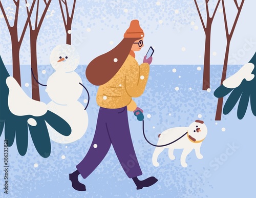 Young woman in warm outerwear walking dog in park and looking in smartphone. Female character with pet in winter forest. Person walk in snowy weather. Vector flat cartoon illustration.