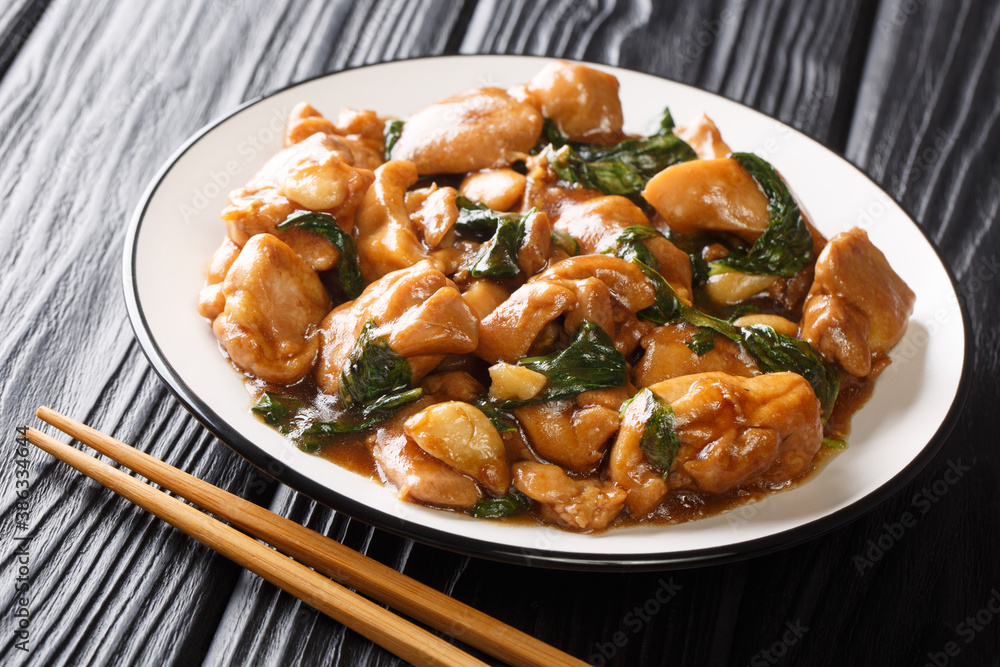 Chinese cuisine three cup chicken in a spicy sauce with basil close-up in a plate on the table. horizontal