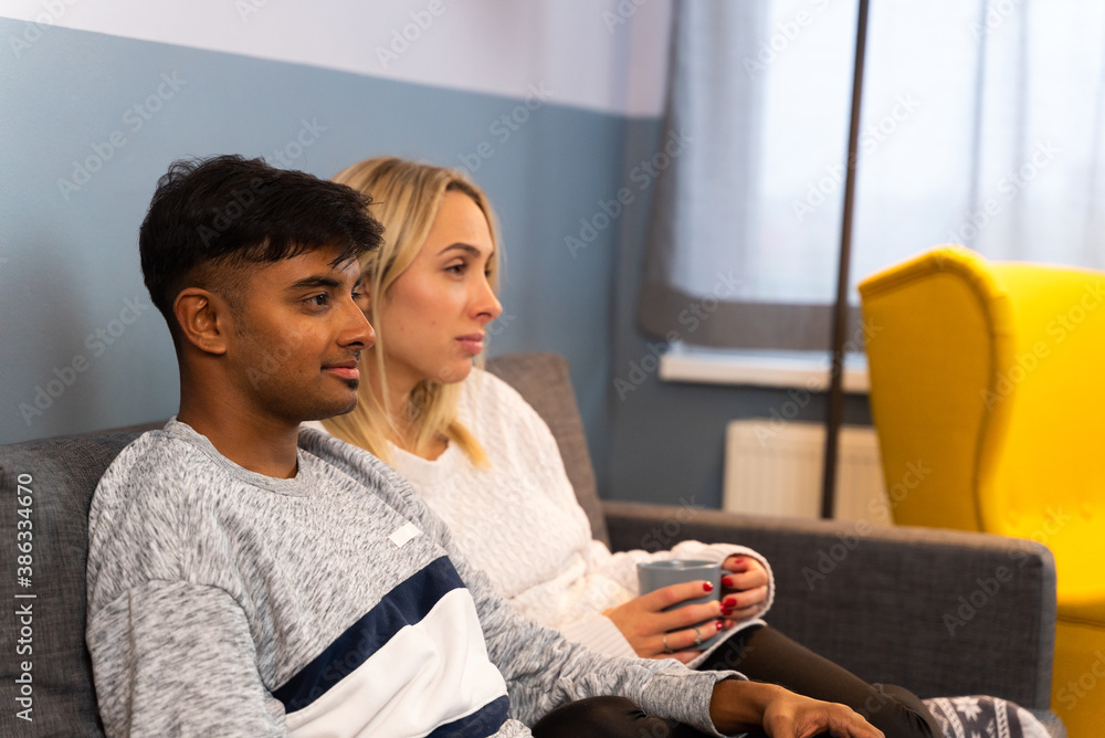 Young and adorable couple watching TV together during the morning breakfast. Young and adorable couple watching TV together during the morning breakfast.