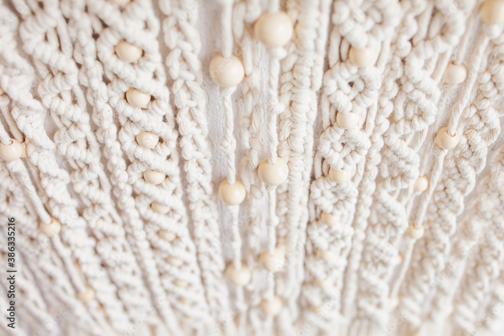 Close-up of hand made macrame texture pattern. Eco friendly modern knitting. Natural decoration concept in the interior. Handmade macrame wall hanging 100% cotton and wooden beads. Soft fokus Close-up of hand made macrame texture pattern. Eco friendly modern knitting. Natural decoration concept in the interior. Handmade macrame wall hanging 100% cotton and wooden beads. Soft fokus