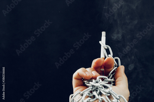 Male hand in metal chains holding cigarette