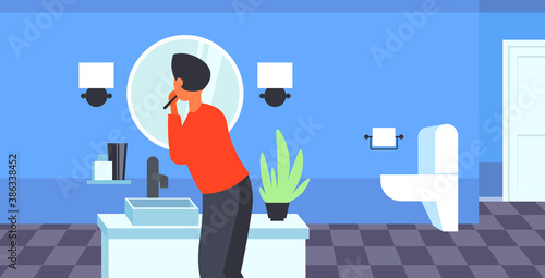 man looking to mirror brushing teeth with toothbrush health care dental hygiene concept modern bathroom interior rear view horizontal portrait vector illustration