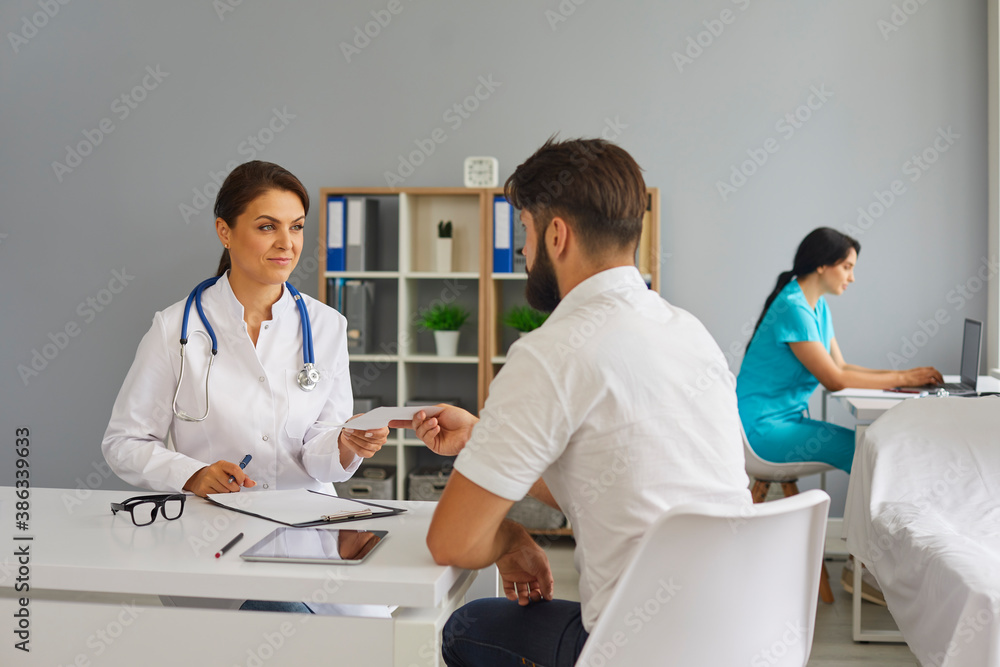Fototapeta premium The doctor gives the patient a prescription while sitting at the table in the office of the clinic.Medical consultation.