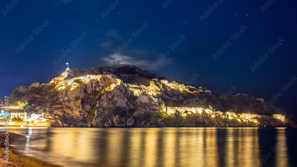 The castle of the city of Myrina on the island of Lemnos photographed at blue hour. Behind the sea and the beach.
